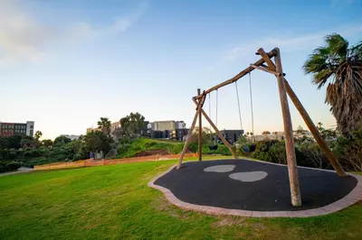 a playground in a park with a swing at Modern Studio Steps from Ratanga Park in Cape Town
