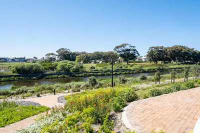 a garden with a river and a pathway at S500 Riverlands - Lux Studio Apartment in Cape Town