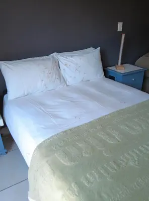 a bed with white sheets and flowers on it at Studio Flat Bayside in Cape Town