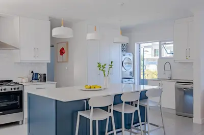 a kitchen with a blue island with bar stools at Serenity on 6th Luxury holiday home in Hermanus