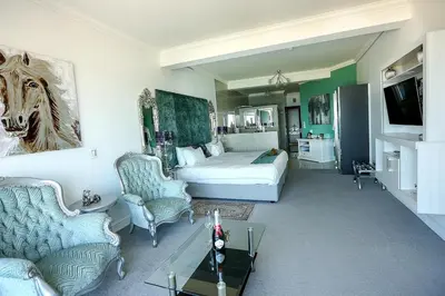 a bedroom with a bed and a couch and a table at Misty Waves Boutique Hotel in Hermanus