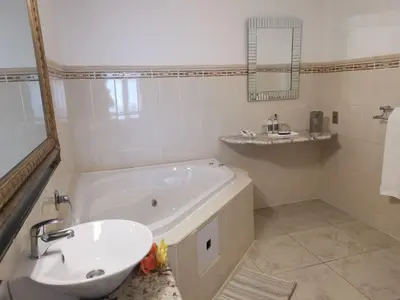 a white bathroom with a tub and a sink at Misty Waves Boutique Hotel in Hermanus