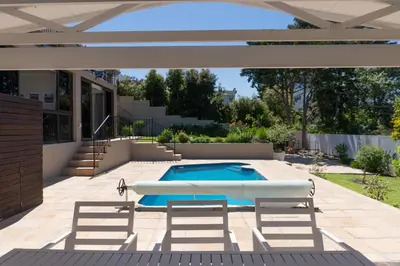 a swimming pool in a backyard with a pergola at Begonias Eden in Helderberg