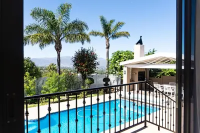 a balcony with a swimming pool and palm trees at Begonias Eden in Helderberg