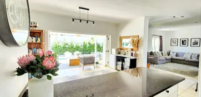 a living room with a vase of flowers on a counter at Tranquil Holiday Home with Pool & Garden 4 bedrooms in Cape Town