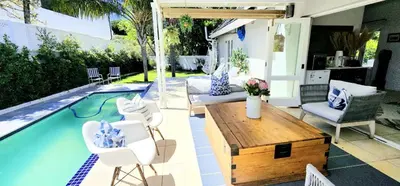 a patio with a table and chairs and a pool at Tranquil Holiday Home with Pool & Garden 4 bedrooms in Cape Town