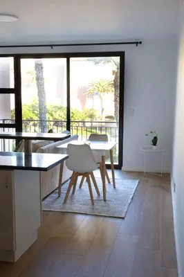a kitchen and dining room with a table and chairs at Island Club Apartment in Cape Town