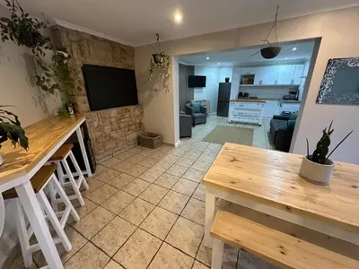 a living room with a table and a kitchen at AquaPalms Hideaway - Family Friendly Pool & Hot Tub in Cape Town