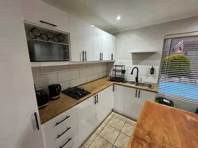 a kitchen with white cabinets and a sink and a microwave at AquaPalms Hideaway - Family Friendly Pool & Hot Tub in Cape Town