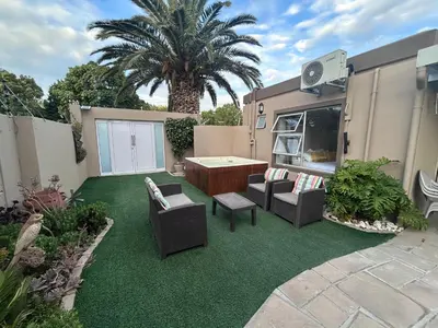 a patio with chairs and a table and a palm tree at AquaPalms Hideaway - Family Friendly Pool & Hot Tub in Cape Town