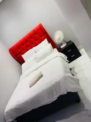 a white bed with a red headboard and white pillows at Plattekloof Queens Guest House in Welgelegen