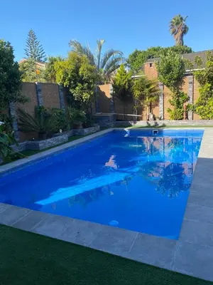 a large blue swimming pool in a yard at Plattekloof Queens Guest House in Welgelegen