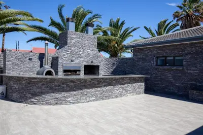 a brick house with palm trees in the background at Plattekloof Queens Guest House in Welgelegen