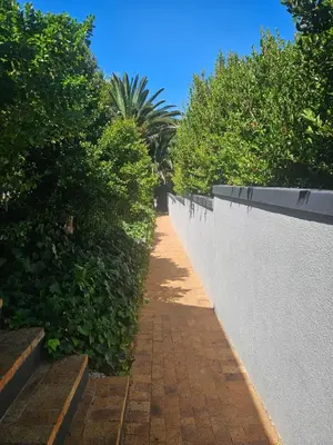 a brick walkway next to a white retaining wall at Fair View in Somerset West