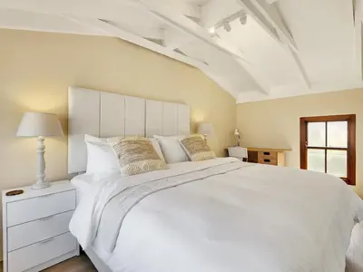 a white bedroom with a large white bed and a window at Luxury beachfront villa Cape Town - Sunset Beach in Cape Town