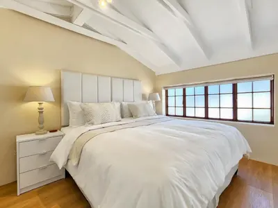 a white bedroom with a large bed and a window at Luxury beachfront villa Cape Town - Sunset Beach in Cape Town