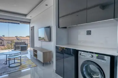 a kitchen with a washing machine and a table at Greystone Serenity 2-Bedroom Apartment in Cape Town