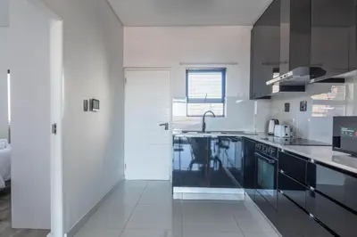 a kitchen with black and white cabinets and a sink at Greystone Serenity 2-Bedroom Apartment in Cape Town