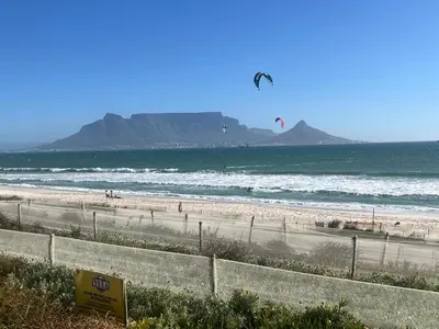 a beach with people flying kites in the ocean at Greystone Serenity 2-Bedroom Apartment in Cape Town