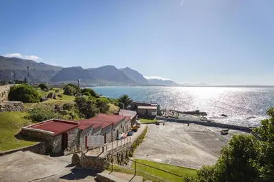 a building on the shore of a body of water at Waterfront Studios - Hermanus Waterfront Apartments in Hermanus