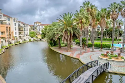 a canal in a resort with palm trees and a bridge at Majorca Apartments by BON Hotels in Cape Town