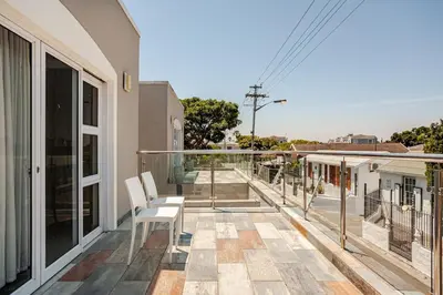 a balcony with two white chairs on a house at Cassamo house in Cape Town