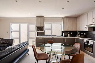 a kitchen with a glass table and chairs at Cassamo house in Cape Town