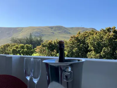 a bottle of wine sitting on a table with wine glasses at The Wild Oak in Hermanus