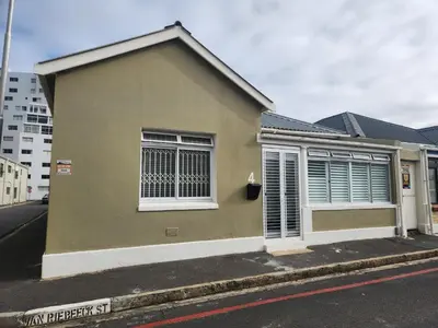 a brown house with white windows on a street at Strand Beach House in Strand