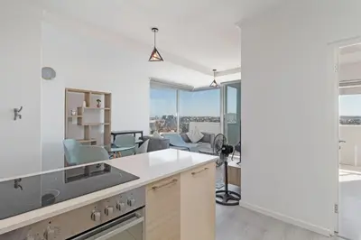 an open kitchen with a view of a living room at Stylish 2-Bedroom Sea-View Apartment Horizon Bay Blouberg Beachfront in Cape Town