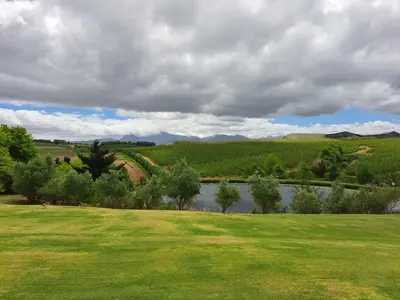 a grassy field with a river in the distance at Glengarry in Grabouw