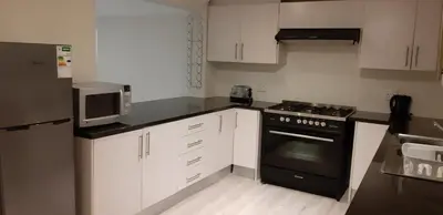 a kitchen with white cabinets and a black stove top oven at Cottage on Abelia in Helderberg
