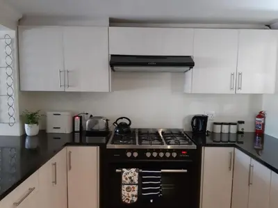 a kitchen with a black stove and white cabinets at Cottage on Abelia in Helderberg