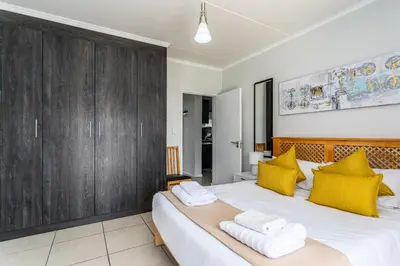 a bedroom with a large bed with yellow pillows at The Sandown 178 by CTHA in Cape Town