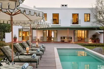 a house with a swimming pool with chairs and an umbrella at Spier Hotel and Wine Farm in Stellenbosch