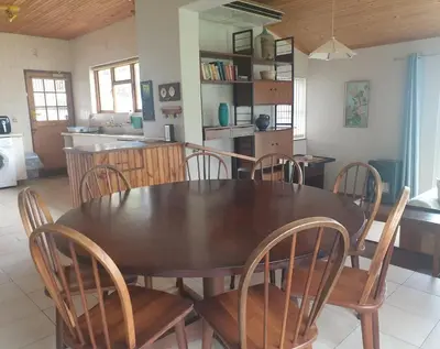 a dining room with a wooden table and chairs at Happidaze in Hermanus