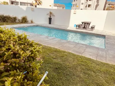 a swimming pool with chairs in a yard at Beach Front in Cape Town