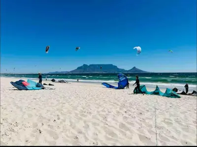 a group of people on a beach flying kites at Beach Front in Cape Town