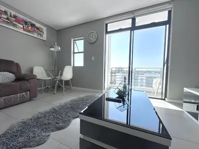 a living room with a couch and a glass table at Beach Front in Cape Town