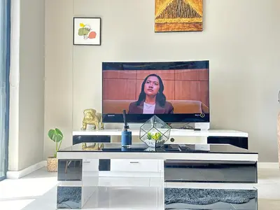 a living room with a tv with a woman on the screen at Beach Front in Cape Town