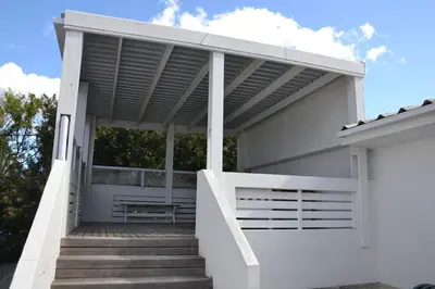 a white house with a pergola on the stairs at Voëlklip House - Home with Pool & Mountain views in Hermanus