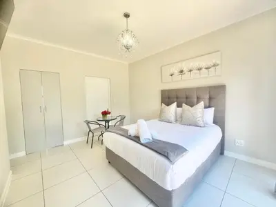a bedroom with a bed and a table and a chandelier at Villa Sunn in Cape Town