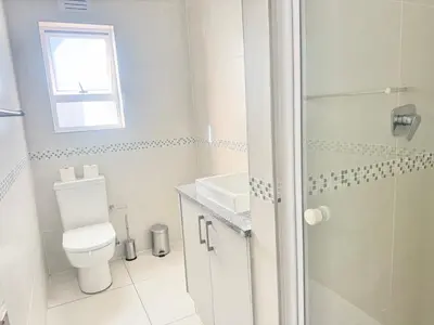 a white bathroom with a toilet and a shower at Villa Sunn in Cape Town