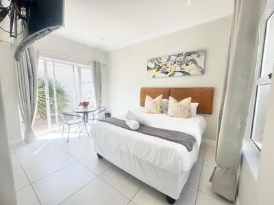 a white bedroom with a bed and a table at Villa Sunn in Cape Town