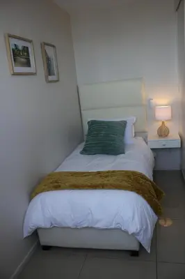 a bedroom with a bed with a green pillow at Luxurious 3-bedroom Bloubergstrand Cape Town beachfront apartment with stunning sea and beach view in Cape Town
