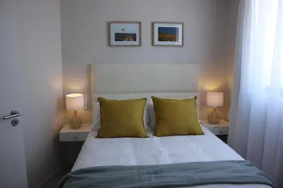 a bedroom with a bed with two lamps on it at Luxurious 3-bedroom Bloubergstrand Cape Town beachfront apartment with stunning sea and beach view in Cape Town