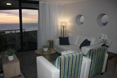 a living room with white furniture and a view of the ocean at Luxurious 3-bedroom Bloubergstrand Cape Town beachfront apartment with stunning sea and beach view in Cape Town
