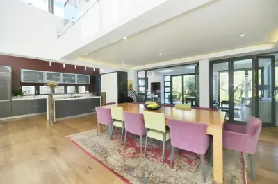 a kitchen and dining room with a wooden table and purple chairs at On Golf Estate Sea & Mountain Views Design Winner in Hermanus