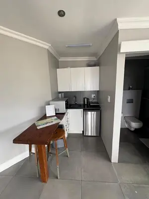 a kitchen with white cabinets and a wooden table at Apartment Dolphin House in Hermanus