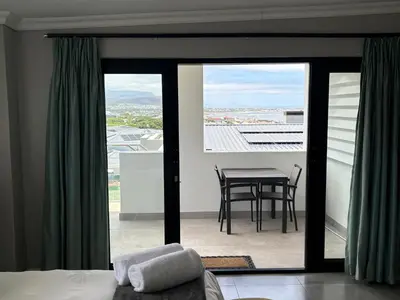 a bedroom with a view of a table and a balcony at Apartment Dolphin House in Hermanus